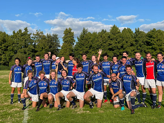 Photo of the Paris Gaels GAA football team. It's a sunny day and they're wearing blue jerseys. Mixed team with women and men of varying ages.